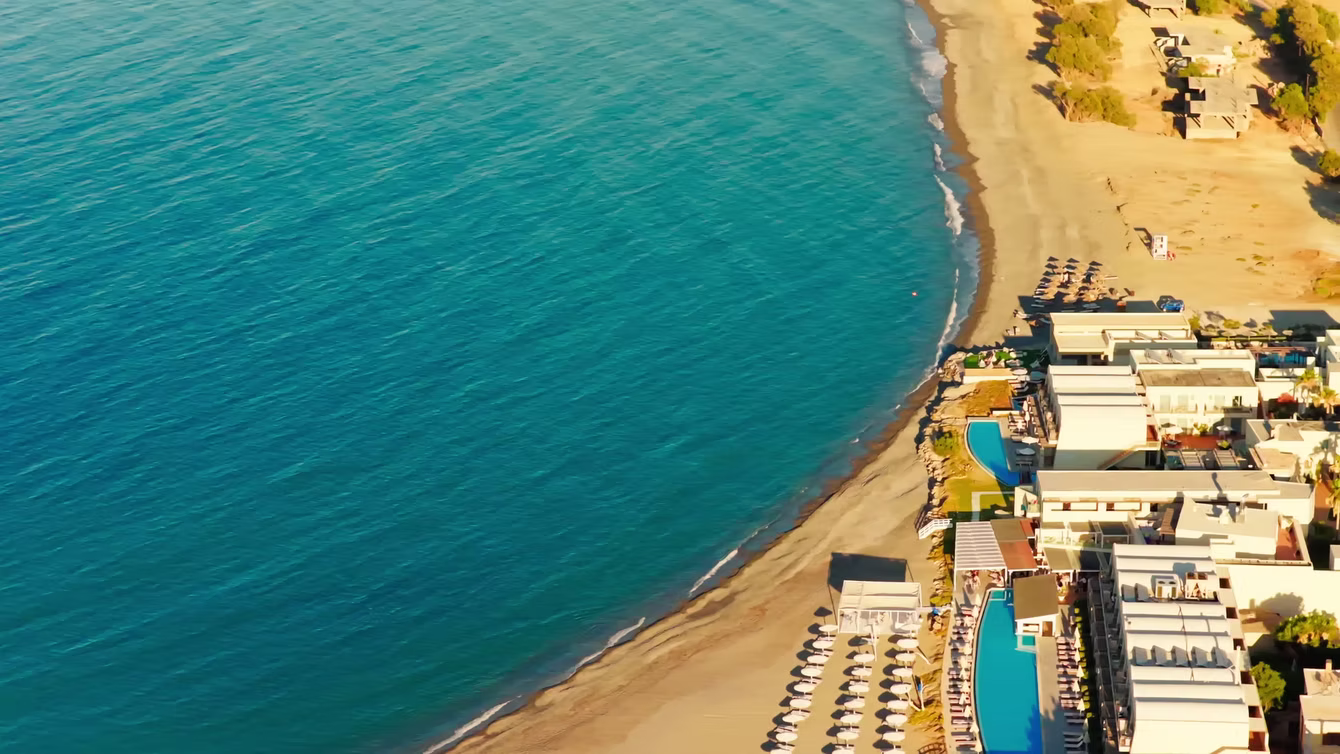Aerial view of a beach resort and turquoise bay lined with sun loungers