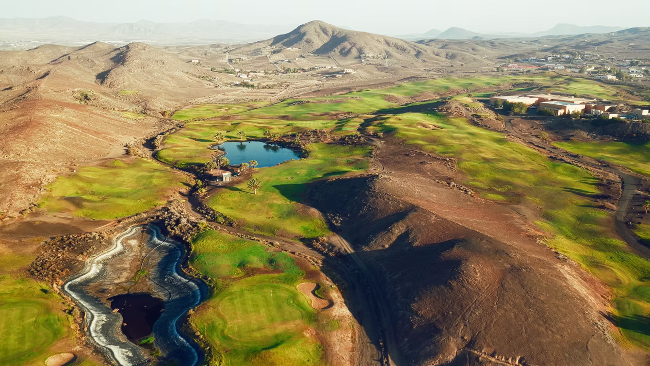 Volcanic coastline meeting the green fairways of a golf course