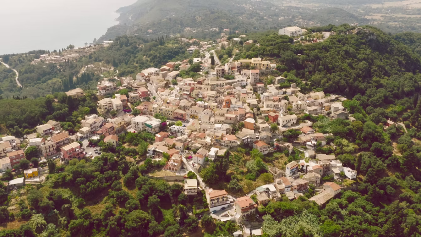 Aerial view of a whitewashed coastal town among green hills